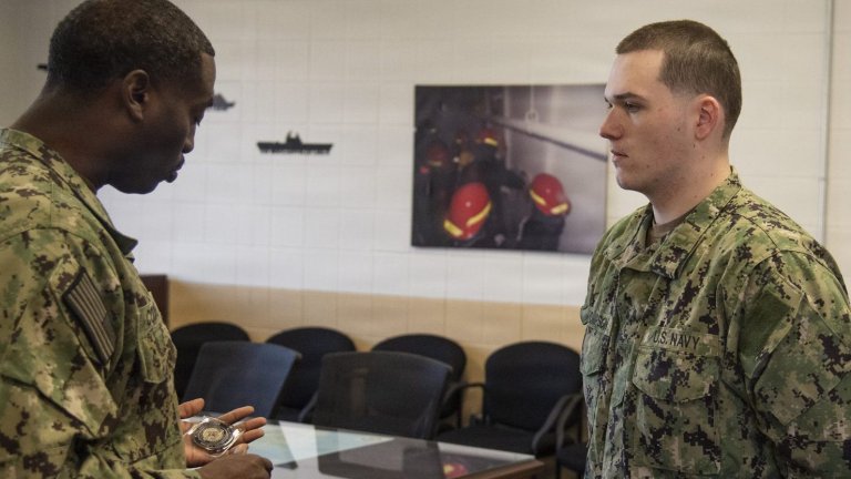 NAVAL STATION GREAT LAKES (November 3, 2025) — Fireman William Thompson, right, a native of Seale, Ala., and student at Surface Warfare Engineering Schools Command (SWESC) Great Lakes, receives a command challenge coin from Commanding Officer Cmdr. Quentin Cooper, Nov. 3, for his role in rescuing a man from a flame-engulfed vehicle. Oct. 25. Thompson dove into action by breaking open a car's window after noticing it had caught fire and filled with smoke on the upper level of a mall's parking garage in Schaumberg, Ill. SWESC is responsible for providing technical training to every surface Navy engineer, quartermaster, boatswain and deck seaman; preparing each Sailor to perform on U.S. Navy ships operating around the globe. (U.S. Navy photo by Mass Communication Specialist 1st Class Brian T. Glunt)