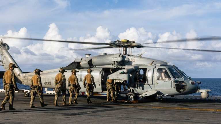 CARIBBEAN SEA – U.S. Marines with the Maritime Special Purpose Force, 22nd Marine Expeditionary Unit (Special Operations Capable), enter a board a U.S. Navy MH-60S Sea hHawk helicopter with Helicopter Sea Combat Squadron (HSC) 26, Iwo Jima Amphibious Ready Group, during fast rope insertion drills while aboard the U.S. Navy Wasp-class amphibious assault ship USS Iwo Jima (LHD 7), IWOARG, while underway in the Caribbean Sea, Oct. 23, 2025. U.S. military forces are deployed to the Caribbean in support of the U.S. Southern Command mission, Department of War-directed operations, and the president’s priorities to disrupt illicit drug trafficking and protect the homeland. (U.S. Marine Corps photo by Sgt. Tanner Bernat)