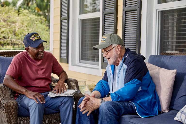 Two senior men sitting and talking on porch