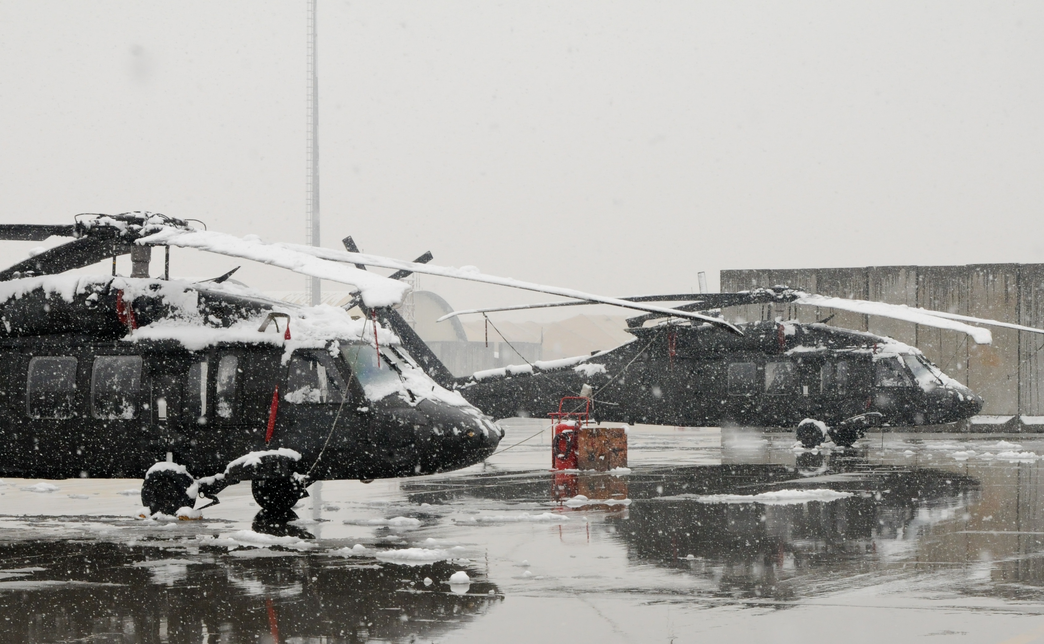 Two Black Hawks from Task Force Lift, 159th Combat Aviation Brigade, 101st Airborne Division are covered in snow after a winter storm blankets Bagram Air Field, Afghanistan.