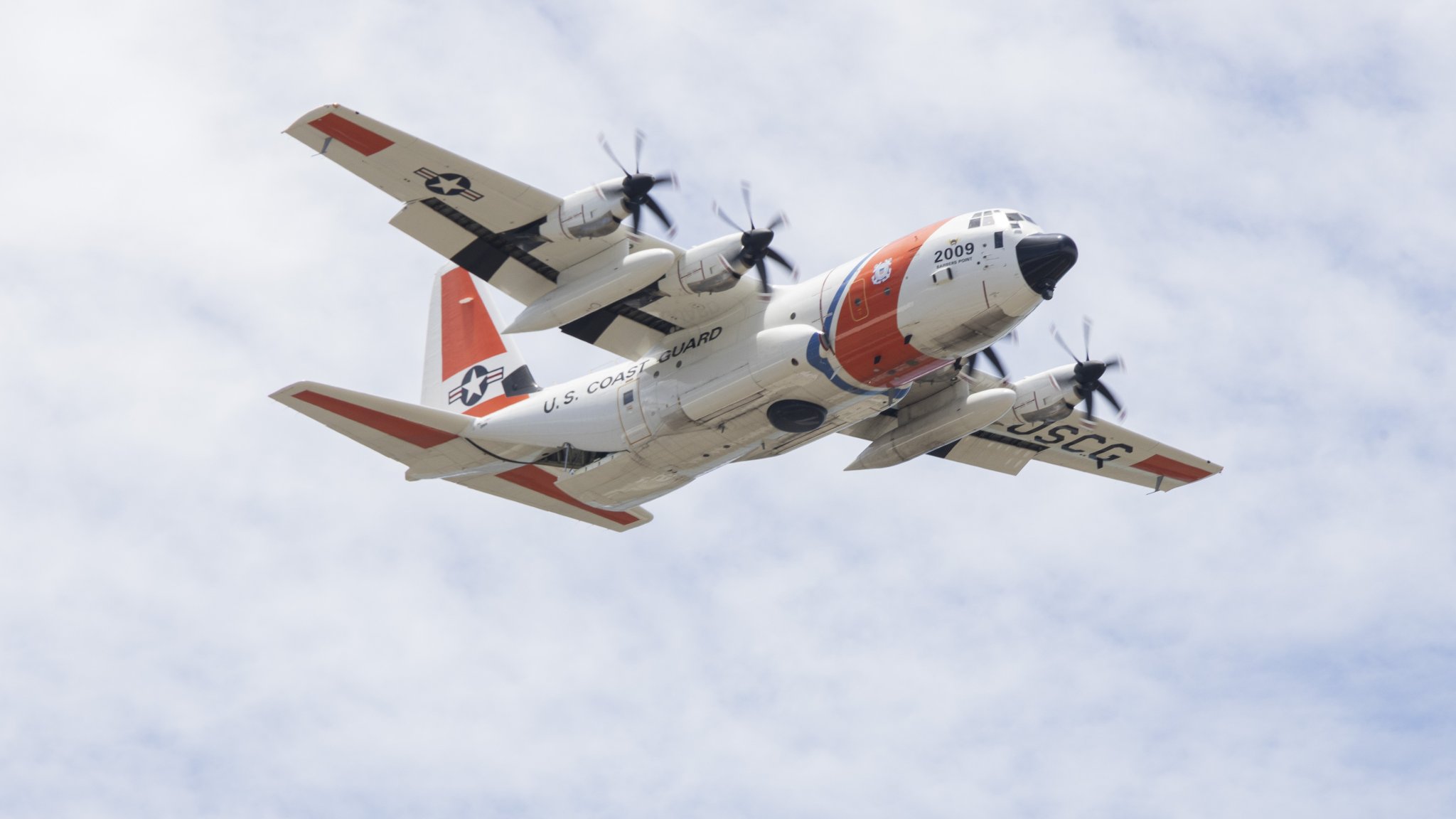A U.S. Coast Guard C-130 Hercules with USCG Base Honolulu, performs aerial maneuvers while performing a Search and Rescue demonstration during the 2025 Kaneohe Bay Air Show at Marine Corps Base Hawaii, Aug. 10, 2025. The Kaneohe Bay Air Show provides an opportunity to showcase the aircraft, equipment and capabilities of the armed forces in the Indo-Pacific region to the local community. The air show contained aerial performances, static displays, demonstrations and vendors, was designed to celebrate MCBH’s longstanding relationship with the local community. (U.S. Marine Corps photo by Cpl. Jade K. Venegas)