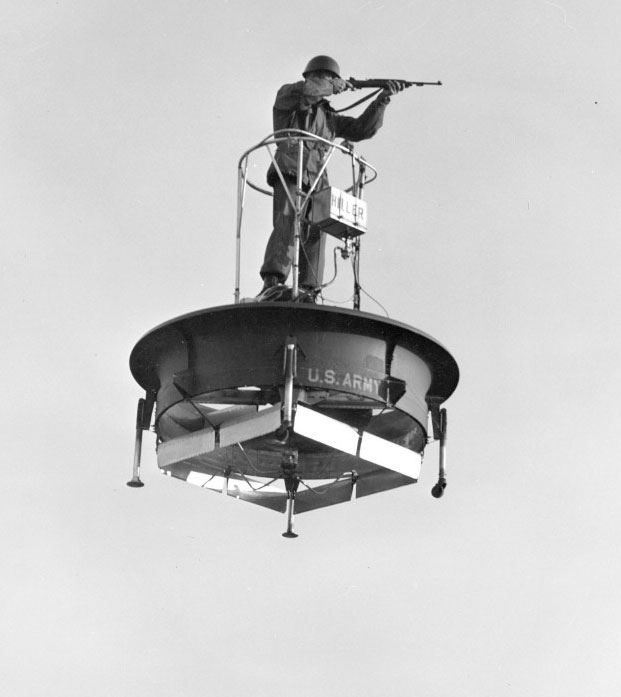 A soldier aims a rifle while airborne on a 1031-A-1 flying platform.