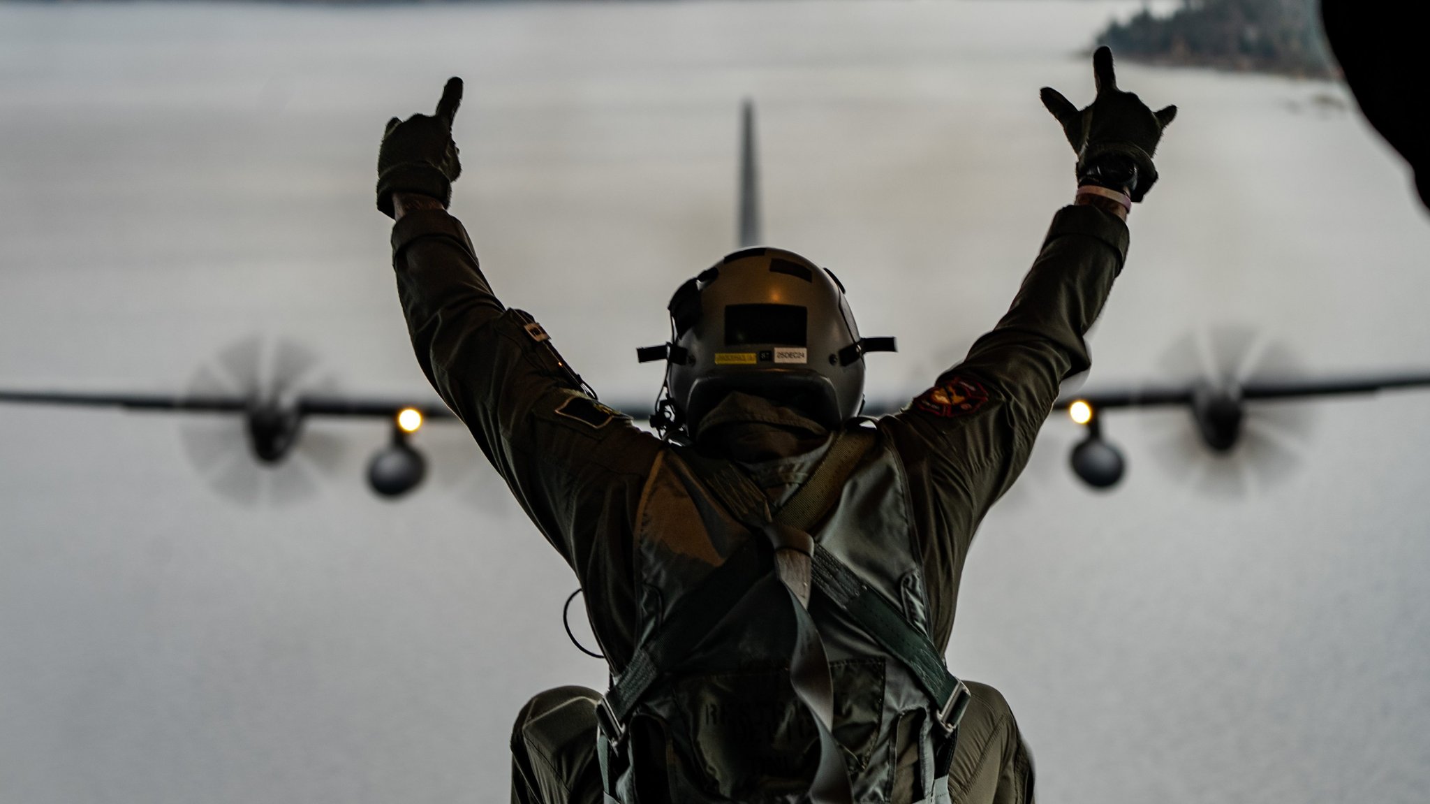 A Nevada Air National Guard C-130H flies above Lake Tahoe during a "spouse lift" while Master Sgt. Billy Johnson, loadmaster with the 192nd Airlift Squadron, sits on the ramp, October 30, 2024. The 152nd Airlift Wing, Nevada Air National Guard, held the spouse lift to explain the mission of the Nevada Air National Guard and to recognize spouses for supporting their military members (Air National Guard photo by Staff Sgt. Michelle Brooks).