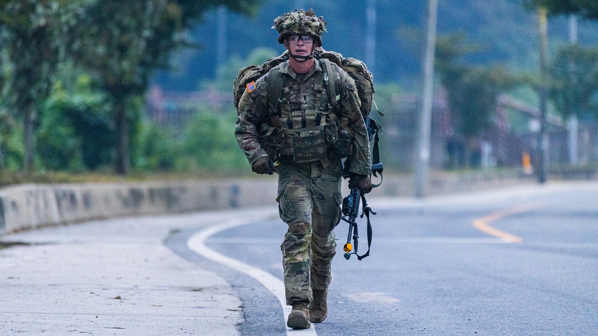 1LT Wesley Sololmon, assigned to 1st Stryker Brigade Combat Team, crosses the finish line as the first-place winner of the 12-mile ruck march during the E2B. The rucking potion demands grit, endurance, and physical fitness in order to succeed within the 3 hour time limit.