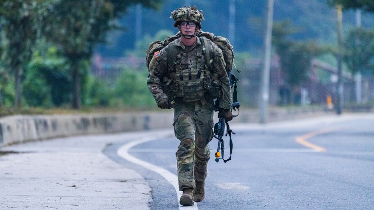 1LT Wesley Sololmon, assigned to 1st Stryker Brigade Combat Team, crosses the finish line as the first-place winner of the 12-mile ruck march during the E2B. The rucking potion demands grit, endurance, and physical fitness in order to succeed within the 3 hour time limit.