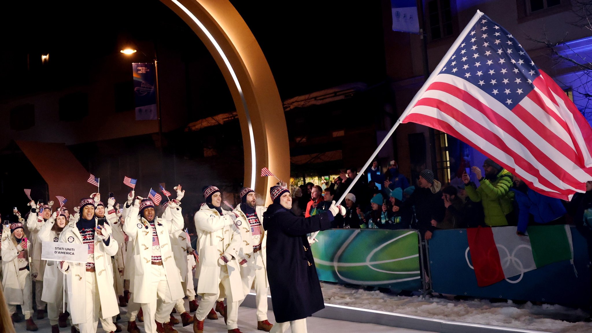 CORTINA D'AMPEZZO, ITALY - FEBRUARY 06: Flagbearer Frankie del Duca of Team United States enters the athlete parade with his team during the opening ceremony of the Milano Cortina 2026 Winter Olympics at Piazza Dibona on February 06, 2026 in Cortina d'Ampezzo, Italy. (Photo by Ezra Shaw/Getty Images)