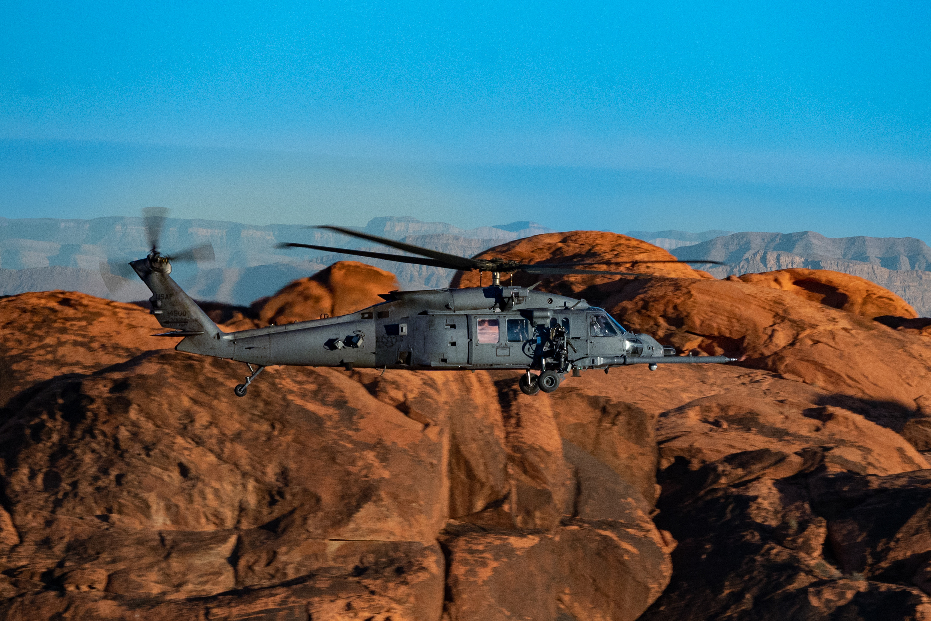 An HH-60W Jolly Green II flies over the Valley of Fire as part of a 53rd Wing civic leader flight from Nellis Air Force Base, Nev., Dec. 12, 2023. The aircraft proceeds the HH-60G Pave Hawk and boasts a digital radar warning receiver, laser missile, hostile fire warning and externally mounted .50 caliber weapons. (U.S. Air Force photo by Airman 1st Class Elizabeth Tan)