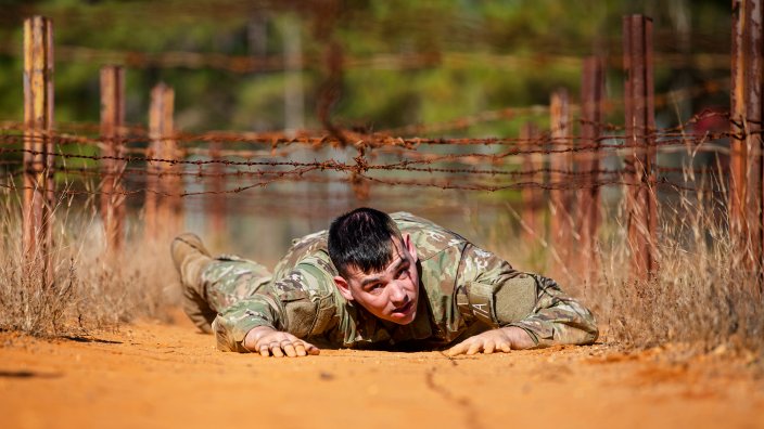 U.S. Army Sgt. 1st Class Joshua Mordenti, representing the Public Health Command - Atlantic, low crawls under barbed wire during the Obstacle Course event for the Regional Health Command-Atlantic 2021 Best Medic Competition at Fort Bragg, North Carolina, Nov. 16, 2021. Eleven two-soldier teams competed at the RHC-A 2021 Best Medic Competition, and the winning team will move on to represent the region at the U.S. Army Medical Command’s 2022 Command Sgt. Maj. Jack L. Clark, Jr. U.S. Army Best Medic Competition at Fort Hood, Texas, Jan. 24-28, 2022. (U.S. Army photo by Spc. Rhianna Ballenger)
