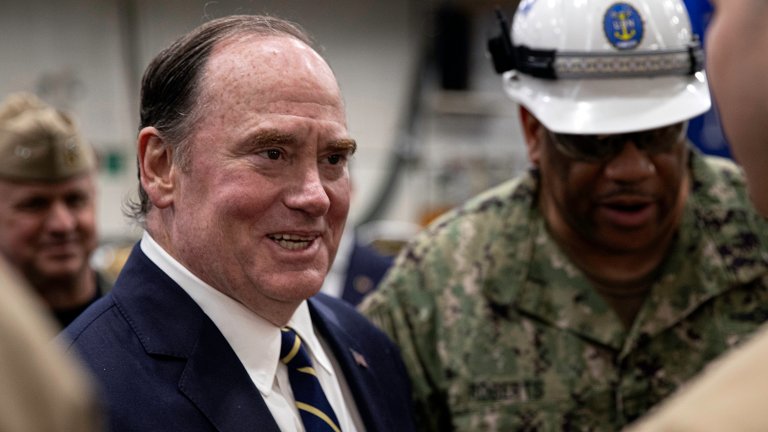 Secretary of the Navy John Phelan speaks to Logistics Specialist 2nd Class Christian Mercado, from Orlando, Florida, assigned to supply department’s material division in the hangar bay aboard Nimitz-class aircraft carrier USS George Washington (CVN 73) while moored pierside at Commander, Fleet Activities Yokosuka, April 28, 2025. George Washington is 7th Fleet’s premier forward-deployed aircraft carrier, a long-standing symbol of the United States’ commitment to maintaining a free and open Indo-Pacific region, while operating alongside Allies and partners across the U.S. Navy’s largest numbered fleet. (U.S. Navy photo by Mass Communication Specialist 3rd Class Tyler Crowley)