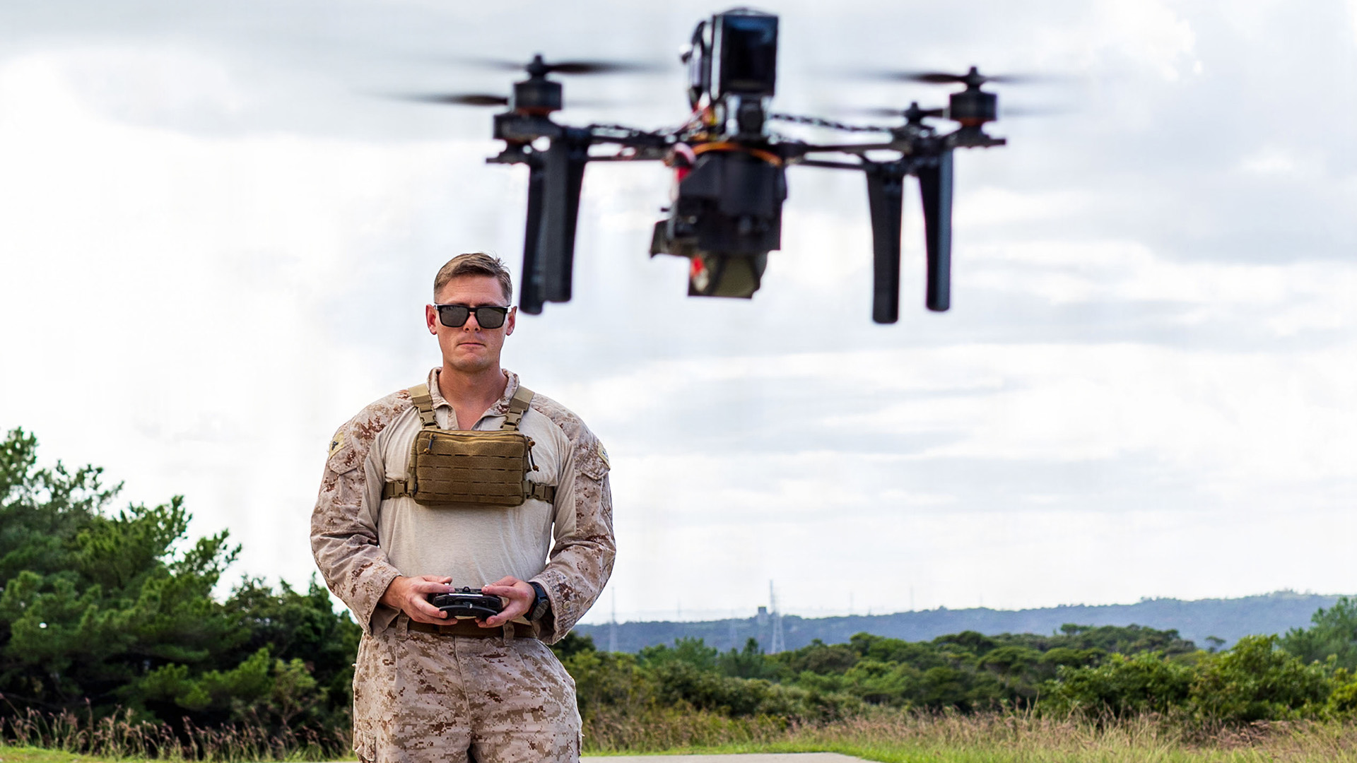 U.S. Marine Corps Cpl. Greg Samarin, a radio operator with Expeditionary Operations Training Group, III Marine Expeditionary Force, flies a drone equipped with an M67 training grenade during an Unmanned Aircraft Systems course demonstration at Camp Hansen, Okinawa, Japan, Nov. 6, 2025. The course instructed Marines on analyzing system capabilities and designing drone configurations for various operational scenarios. The UAS are designed for both remote piloting and autonomous flight, enhancing the Marines' ability to adapt to evolving battlefield requirements. Samarin is a native of California. (U.S. Marine Corps photo by Lance Cpl. Justin Cledera)