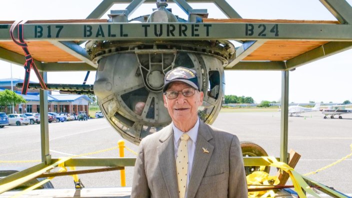 100-year-old retired Staff Sgt. Phillip Bruce Cook stands in front of a B-17 ball turret, like the kind he used to fight in.