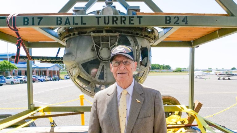 100-year-old retired Staff Sgt. Phillip Bruce Cook stands in front of a B-17 ball turret, like the kind he used to fight in.
