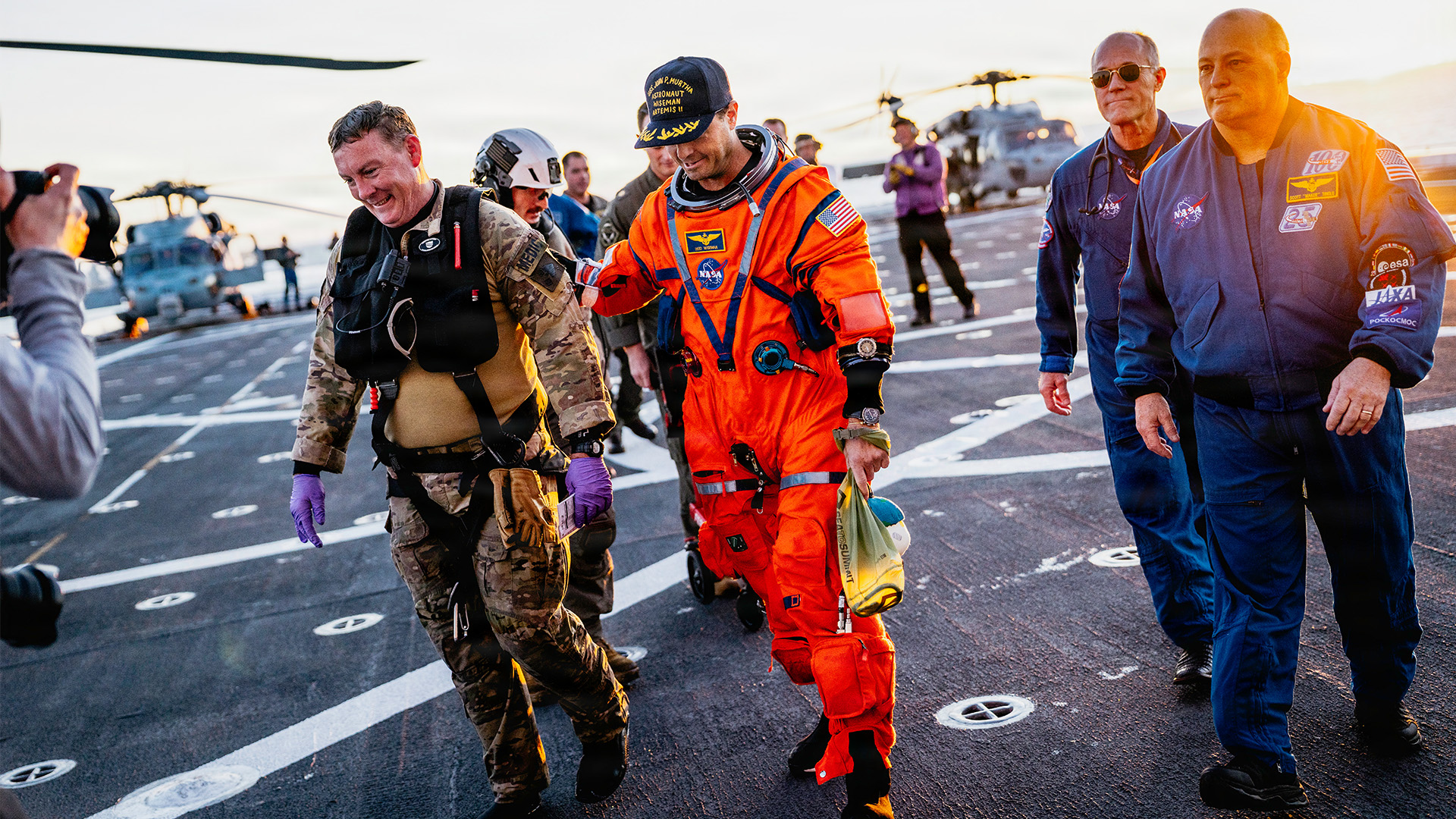 NASA astronaut Reid Wiseman walks with NASA personnel on the flight deck of the San Antonio Class amphibious transport dock USS John P. Murtha after returning from space on Apr. 10, 2026.