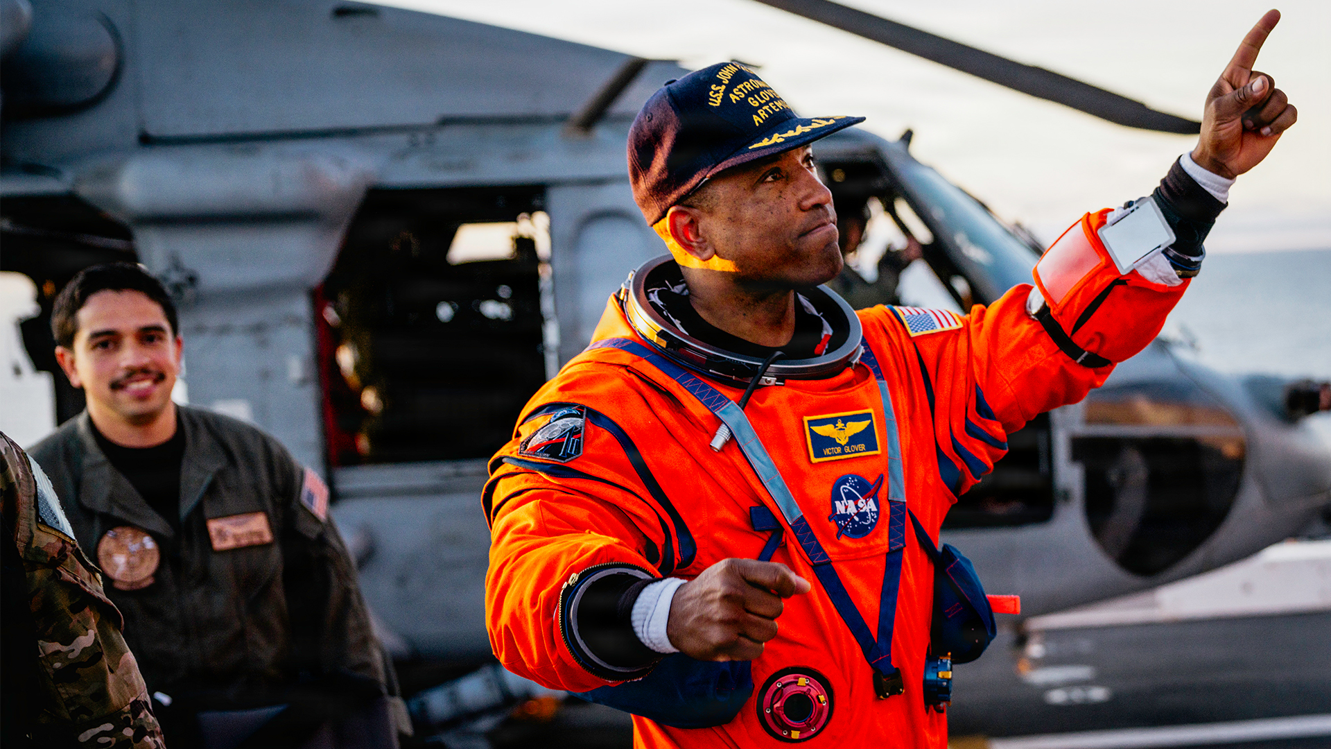 NASA astronaut Victor Glover points at crew members on the flight deck of the San Antonio Class amphibious transport dock USS John P. Murtha (LPD 26) after returning from space on Apr. 10, 2026. John P. Murtha is underway in the U.S. 3rd Fleet area of operations supporting NASA’s Artemis II mission, retrieving the crew and spacecraft following their return to Earth and splashdown in the Pacific Ocean. NASA’s Artemis II mission sent four astronauts on a flight around the moon in the Orion space craft, marking the first time humans journeyed to deep space in over 50 years. (U.S. Navy photo by Mass Communication Specialist 2nd Class August Clawson)