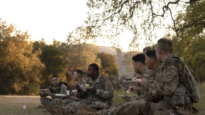 Image: A group of soldier competitors eat dinner in the field after completing a land navigation course during the 2022 Combined Best Warrior Competition at Fort Hunter-Liggett, California, April 1. 15 Soldiers traveled to compete in this year’s Best Warrior, hosted by United States Army Civil Affairs and Psychological Operations Command (Airborne), 84th Training Command, and 108th Training Command (IET) from March 31 through April 5, 2022. Competitors are evaluated on their individual ability to adapt and overcome challenging scenarios and battle-focused events, which test their technical and tactical abilities under stress and extreme fatigue. (U.S. Army Reserve photo by Spc. Olivia Cowart)