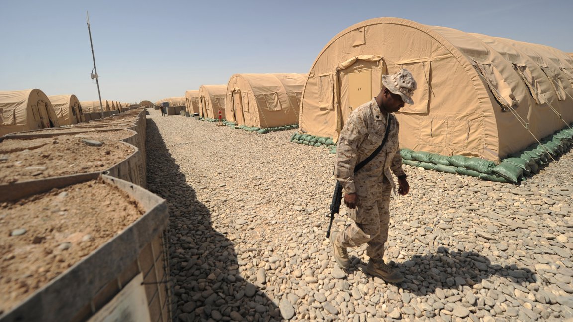 A US marine from Regimental Combat Team-8 walks between accommodation tents at Forward Operating Base Delaram in Helmand province, southern Afghanistan on April 4, 2011. Around 140,000 foreign troops are deployed in Afghanistan within the UN-mandated, NATO-led, International Security Assistance Force (ISAF) and the US-led coalition Operation Enduring Freedom, which overthrew the Taliban in late 2001. AFP PHOTO/Peter PARKS (Photo credit should read PETER PARKS/AFP via Getty Images)