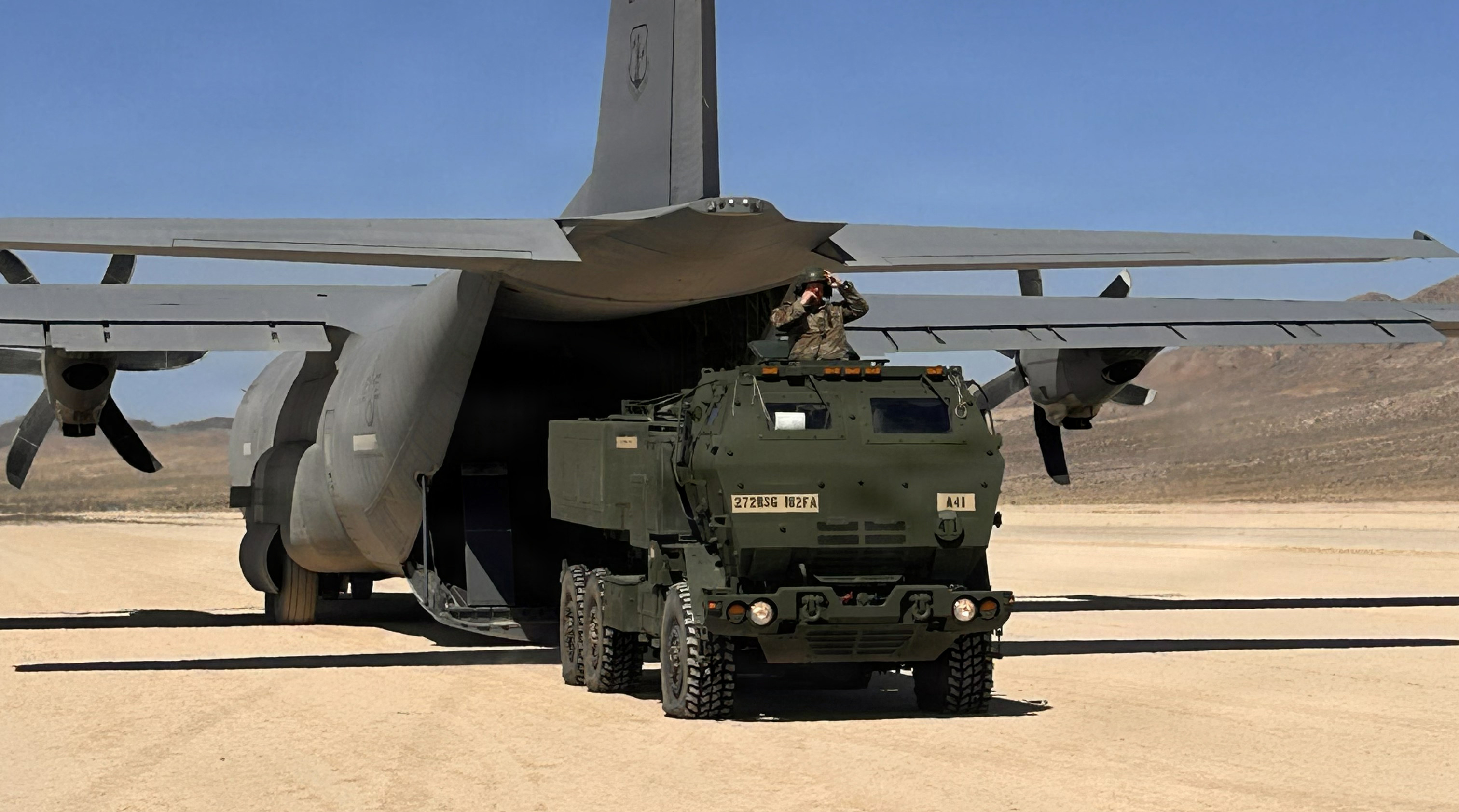 U.S. Army Soldiers with Alpha Battery, 1st Battalion, 182nd Field Artillery Regiment, Michigan Army National Guard, roll offM142 High Mobility Artillery Rocket System (HIMARS) from a C-130J Hercules aircraft at National Training Center, Michigan, June 10, 2026 to conduct a HIMARS Rapid Infiltration (HIRAIN) mission . The movement was part of a Minuteman Rotation at the National Training Center at Fort Irwin, California to conduct a HIRAIN exercise. The HIRAIN demonstrated the unit's capability to rapidly deploy a HIMARS via airlift, execute a strike, and exfiltrate to avoid detection. (U.S. Army National Guard photo by 1st Lt. Daniel Throne)
