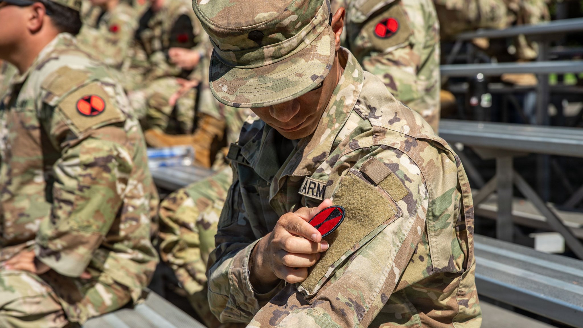 A Soldier assigned to 7th Infantry Division (Multi-Domain Command - Pacific) switches their patch from the 1st Multi-Domain Task Force patch to the 7th ID (MDC-PAC) patch during a redesignation ceremony at Joint Base Lewis-McChord, Wash., June 18, 2026. The redesignation honors the Bayonet Division’s legacy while establishing 7th ID (MDC-PAC) as the Army’s newest theater-enabling command, built to integrate maneuver, fires, air defense, cyber, space, electronic warfare, intelligence, unmanned systems, sustainment, and command and control in support of the Joint Force across the Pacific. (U.S. Army photo by Sgt. Taylor Zacherl) 