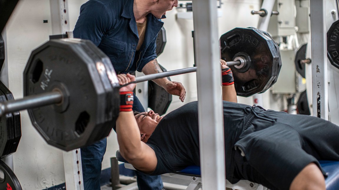 U.S. Marine Corps Lance Cpl. Tyrone Sisneros, a rifleman with Charlie Company, Battalion Landing Team 1/1, 11th Marine Expeditionary Unit, performs a bench press during the 1000-pound club challenge aboard amphibious assault ship USS Essex (LHD 2), Sept. 10, 2021. Essex, flagship of the Essex Amphibious Ready Group, along with the 11th MEU, is operating in the U.S. 7th Fleet area of responsibility to enhance interoperability with allies and partners and serve as a ready response force to defend peace and stability in the Indo-Pacific region. (U.S. Marine Corps photo by Cpl. Israel Chincio)