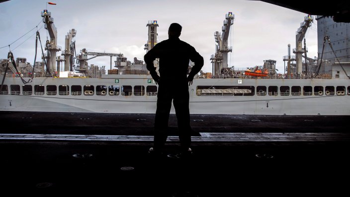 A U.S. Sailor observes a fueling-at-sea between fleet replenishment oiler USNS John Lewis (T-AO-205) and Nimitz-class aircraft carrier USS Abraham Lincoln (CVN 72), June 28, 2026. Abraham Lincoln is deployed to the U.S. 5th Fleet area of operations to support maritime security and stability in the Middle East. (U.S. Navy photo)