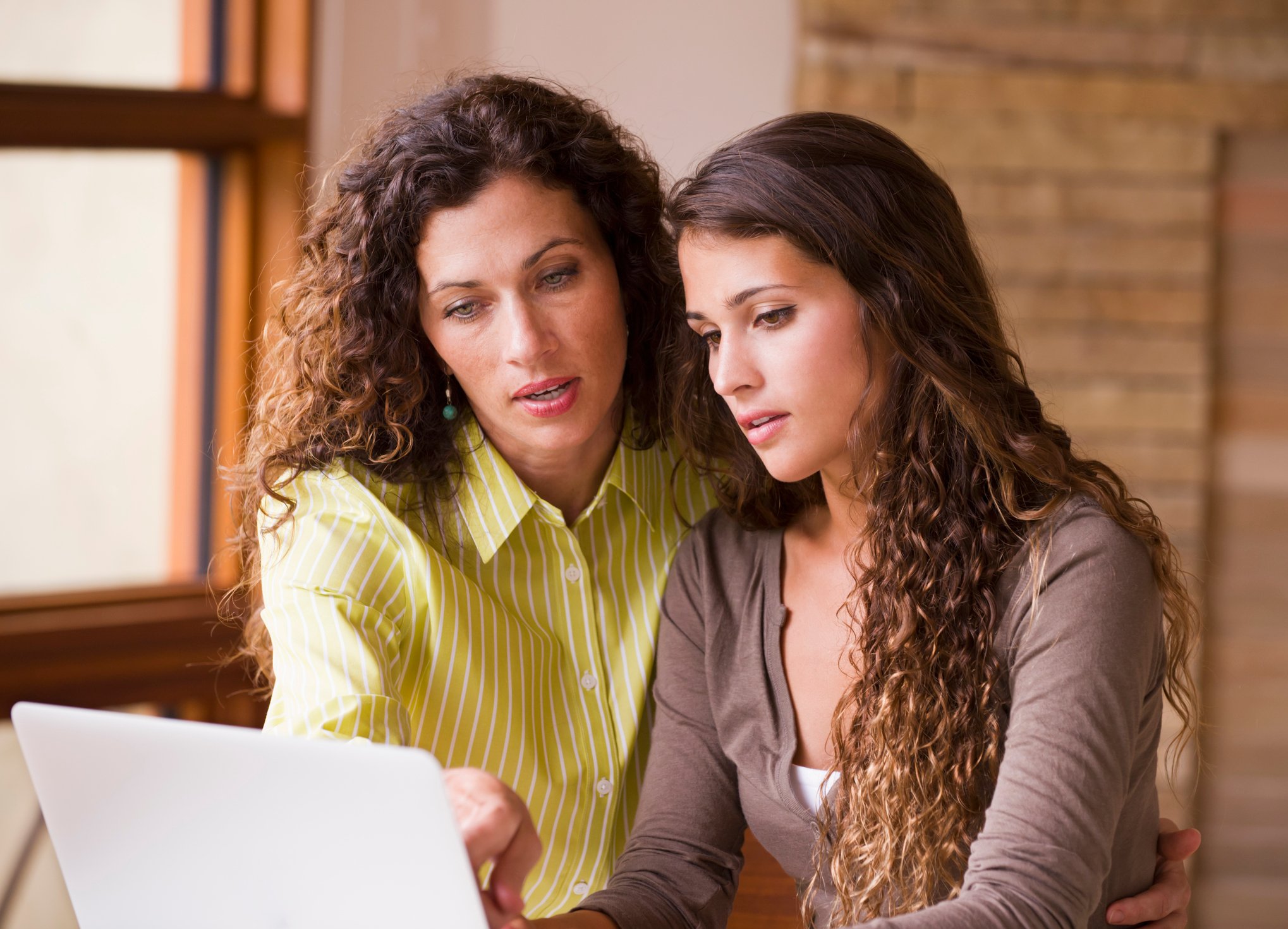 Mixed race mother and daughter using laptop together