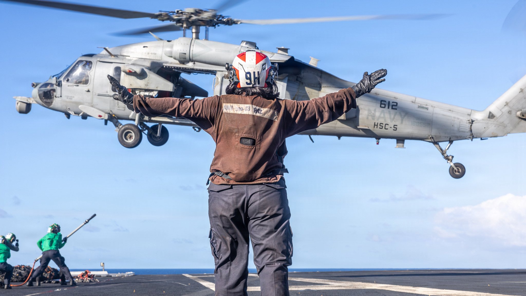 Airman Jenna Paz, assigned to the ’Nightdippers” of Helicopter Sea Combat Squadron (HSC) 5, directs an MH-60S Sea Hawk while conducting a vertical replenishment with with Supply-class fast combat support ship USNS Arctic (T-AOE 8) aboard Nimitz-class aircraft carrier USS George H.W. Bush (CVN 77) in the Indian Ocean, April 19, 2026. The George H.W. Bush Carrier Strike Group is on a scheduled deployment in the U.S. 6th Fleet area of operations to support the warfighting effectiveness, lethality and readiness of U.S. Naval Forces Europe Africa, and defend U.S., Allied and partner interests in the region. (U.S. Navy photo by Mass Communication Specialist Seaman Lucas Krug)
