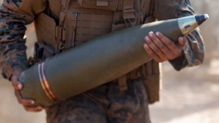 A Marine carries a 155 mm shell during artillery training in 2024. A Texas factory built in 2024 to build 30,000 shells per month has so far built zero.