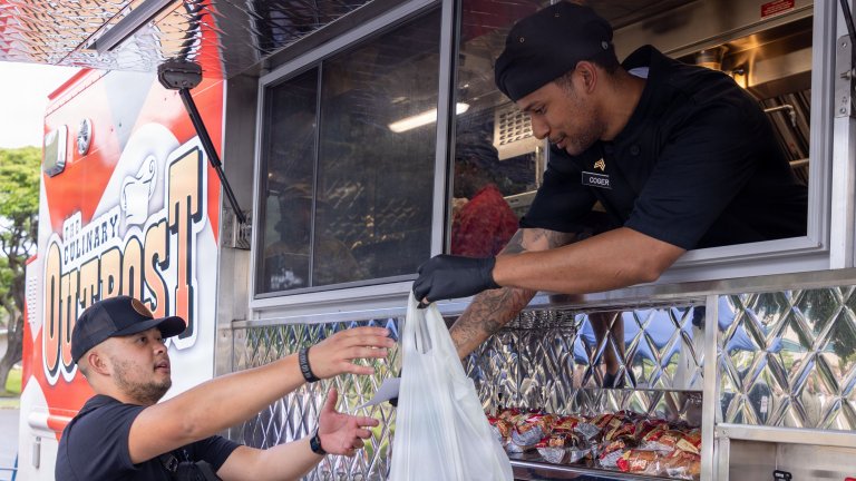 U.S. Army Sgt. Maj. Alethea Ellegor, administrative manager for the Culinary Outpost, serves a meal to a Soldier at the Culinary Outpost at Fort Shafter, Hawaii, June 16, 2026. The Culinary Outpost officially began serving Soldiers that day as part of an effort to enhance quality of life and support readiness by providing fresh, convenient meals designed with Soldiers in mind. (U.S. Army photo by Sgt. Deneisha Owens-McParland)