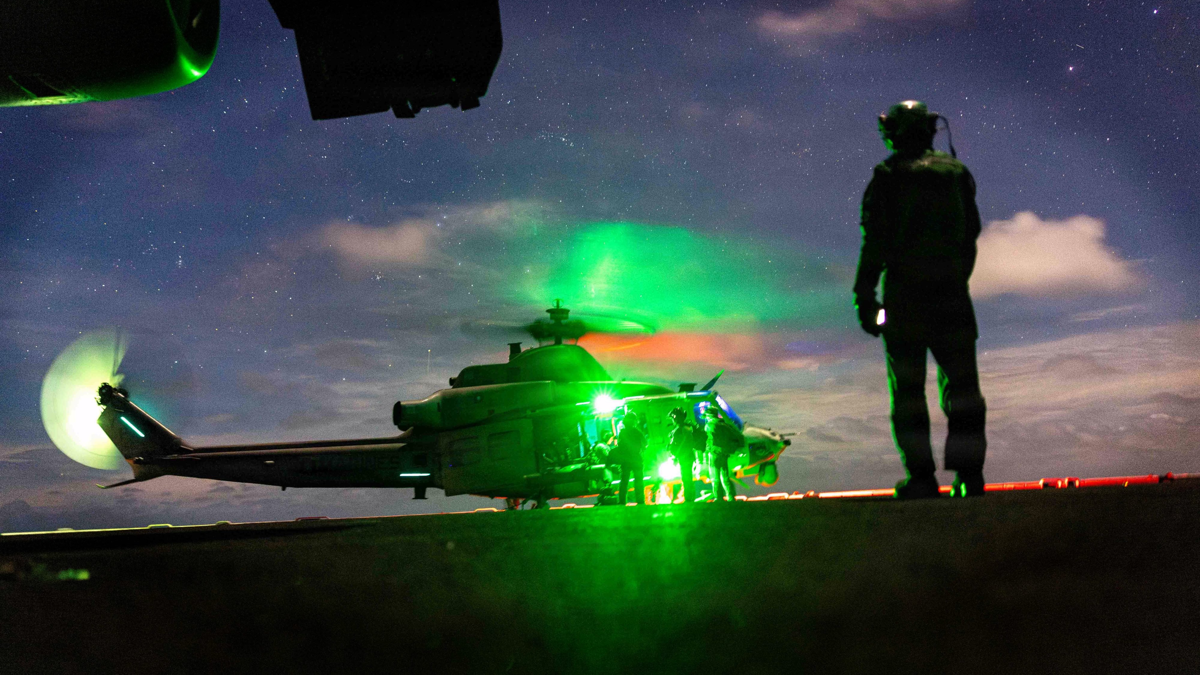 A U.S. Marine with Marine Medium Tiltrotor Squadron (VMM) 163 (Reinforced), 11th Marine Expeditionary Unit observes a UH-1Y Venom assigned to VMM 163 (Rein.), 11th MEU, during flight operations aboard Wasp-class amphibious assault ship USS Boxer (LHD 4) in the Indian Ocean, June 23, 2026. The 11th MEU, embarked aboard the Boxer Amphibious Ready Group, is a persistent, combat credible force contributing to deterrence and crisis response in the U.S. 7th Fleet area of operations. U.S. 7th Fleet, the U.S. Navy's largest forward-deployed numbered fleet, routinely interacts and operates with allies and partners to preserve a free and open Indo-Pacific. (U.S. Marine Corps photo by Sgt. Trent A. Henry)