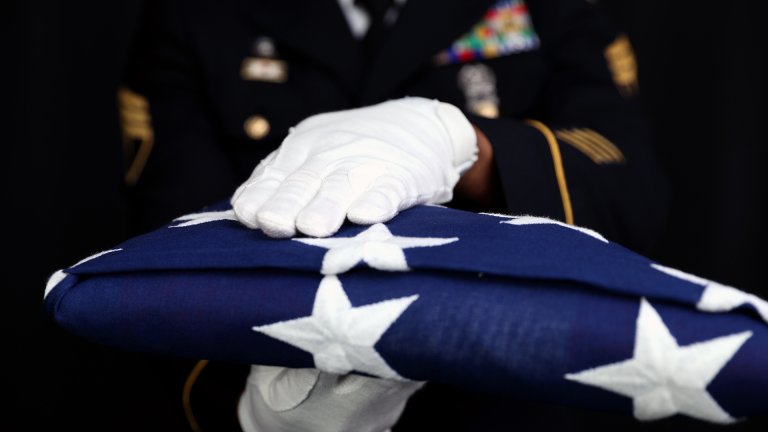 U.S. Army Staff Sgt. Dwayne Calvon, 224th Sustainment Brigade Headquarters and Headquarters Company, California National Guard, holds a folded American flag in a studio at Joint Forces Training Base, Los Alamitos, Calif., July 26, 2022. (U.S. Army National Guard photo by Pfc. Yancy Mendoza.)