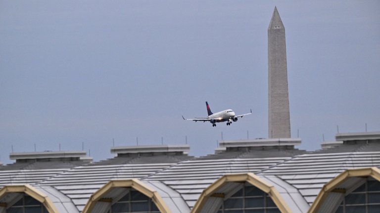 Image: A commercial jet approaches the only working runway at Ronald Reagan International Airport near the Washington Monument (background) and the airport terminal in Arlington, Virginia, on February 2, 2025. Operations to salvage the wreckage from a deadly collision between a US Army helicopter and a passenger jet continued on February 2 as rescuers said 55 victims had so far been identified. Dozens of victims have been pulled from the icy Potomac River, and rescuers voiced confidence that those remaining would be retrieved in the massive operation to recover the plane that collided in midair with a Black Hawk military helicopter. (Photo by ROBERTO SCHMIDT / AFP) (Photo by ROBERTO SCHMIDT/AFP via Getty Images) 